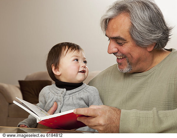 Grandfather reading book to granddaughter
