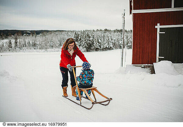 Grandma on old antique sleigh with grandchild in farm in Norway