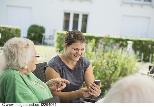 Grandmother and granddaughter discussing over smartphone