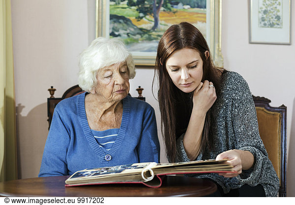 Grandmother and granddaughter looking at photo album