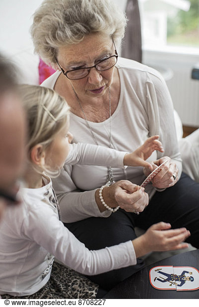 Grandmother and granddaughter playing card puzzle game at home