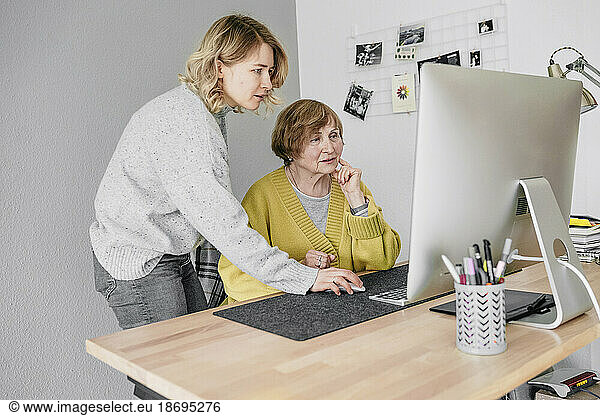 Grandmother and granddaughter using computer at home
