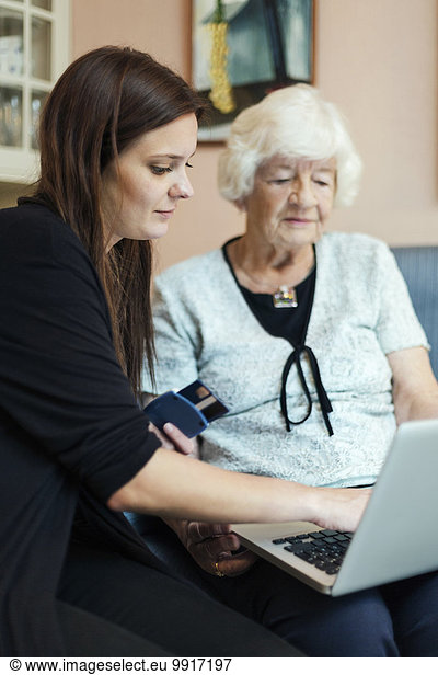 Grandmother and granddaughter using laptop at home