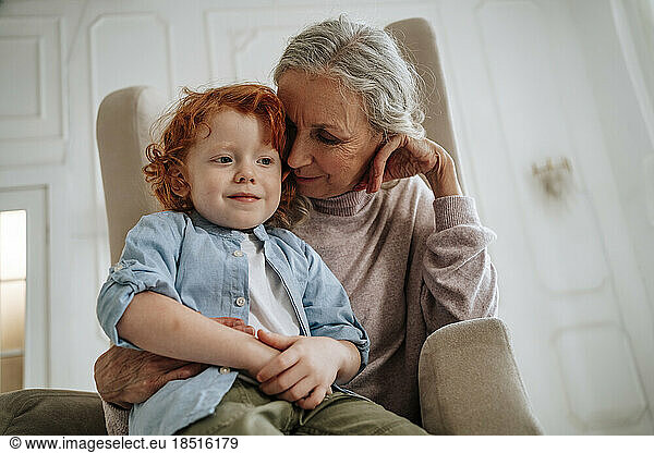 Grandmother and grandson sitting in armchair at home