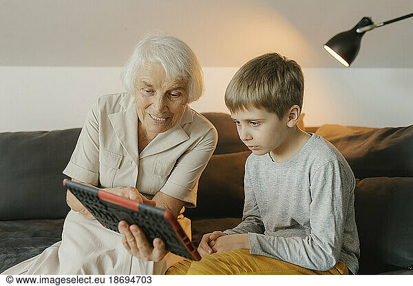 Grandmother and grandson watching video on tablet PC sitting at home