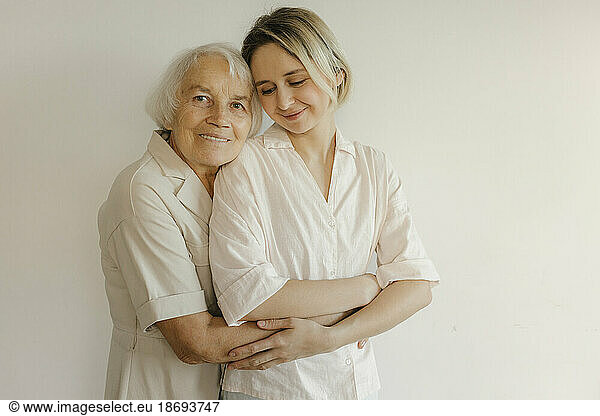 Grandmother embracing granddaughter at home