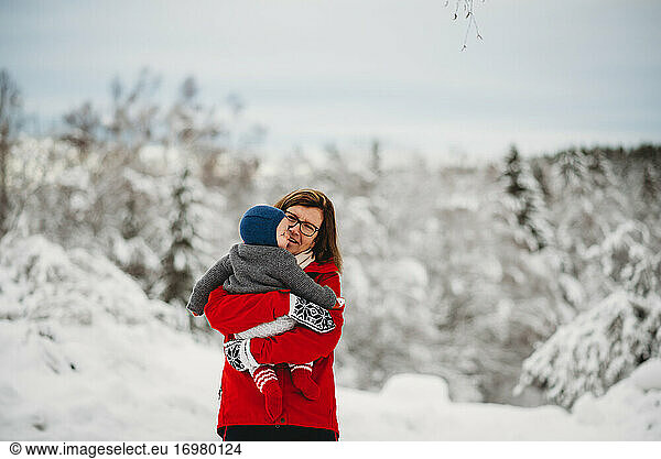 Grandmother holding grandchild baby outside in snow in winter Norway