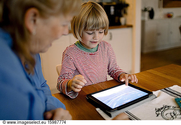 Grandmother looking at grandson using digital tablet