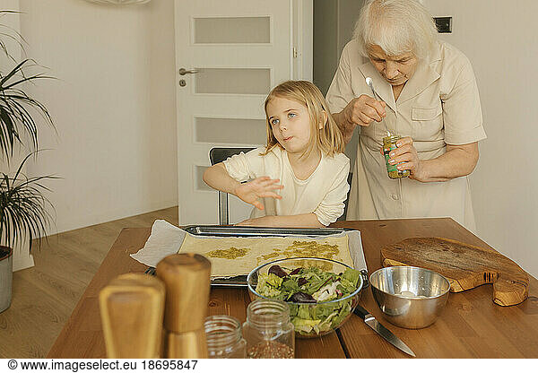 Grandmother preparing food with granddaughter at home
