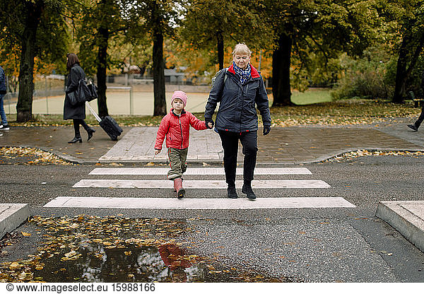 Grandmother walking with grandson on footpath in city