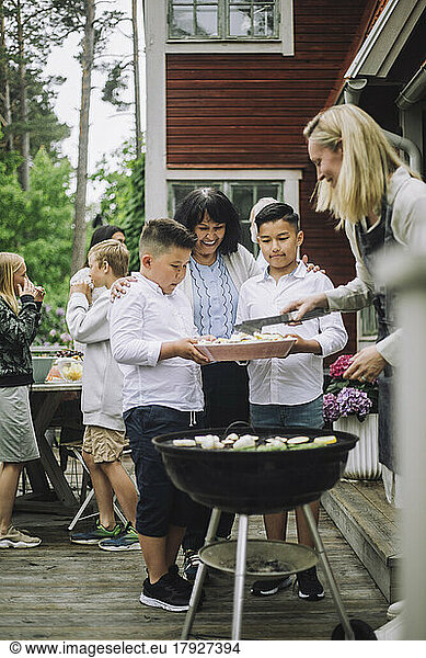 Grandmother with grandchildren taking barbecue food during party