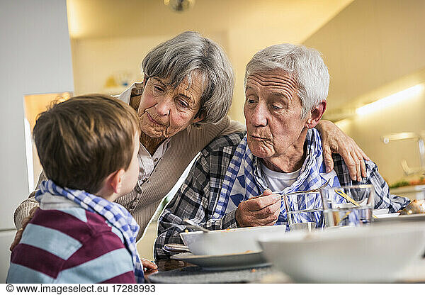Grandparent looking at grandson while having food at home