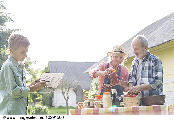 Grandparents and grandson preparing to sell honey