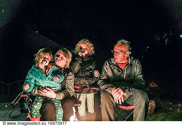 Grandparents sitting with grandchildren around firepit