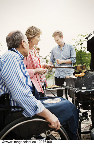 Grandparents with brothers barbecuing at yard