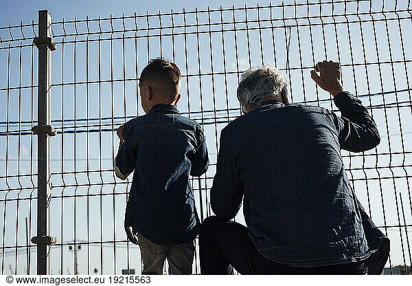 Grandson and grandfather looking through fence