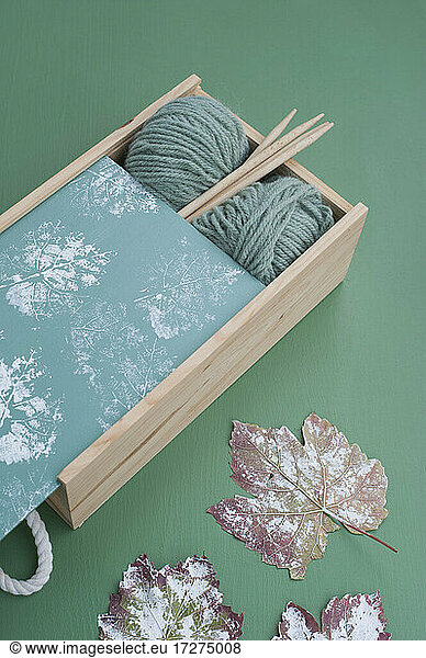 Grape leaves and crate with wool and wooden knitting needles