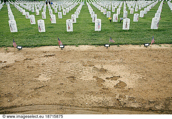 Grass and gravestones border mud from newly dug graves at Section 60 in Arlington National Cemetery