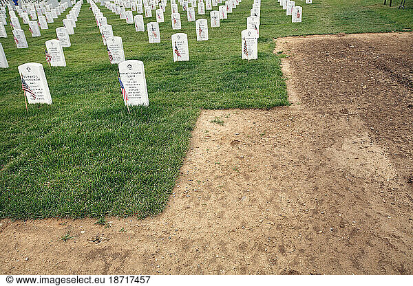 Grass and gravestones border mud from newly dug graves at Section 60 in Arlington National Cemetery