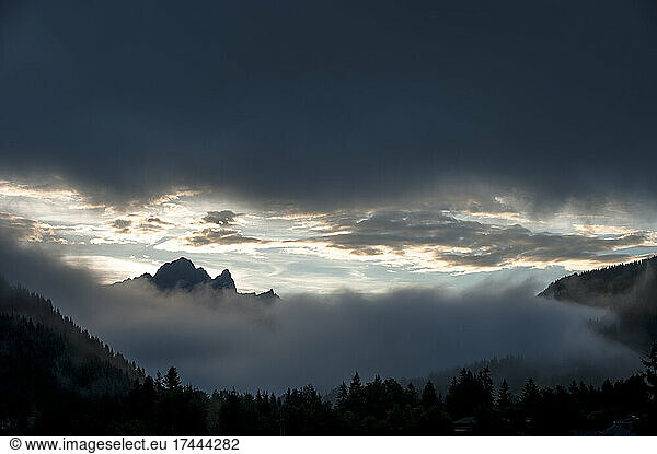 Gray clouds over thick fog in Ennstal Alps at dusk
