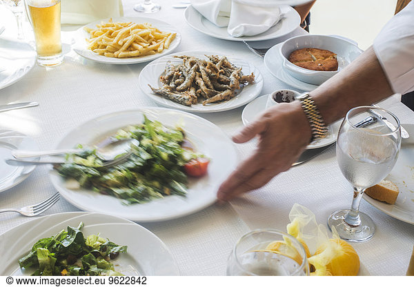 Greece  Athens  Piraeus  hand of waiter arranging plate od laid table