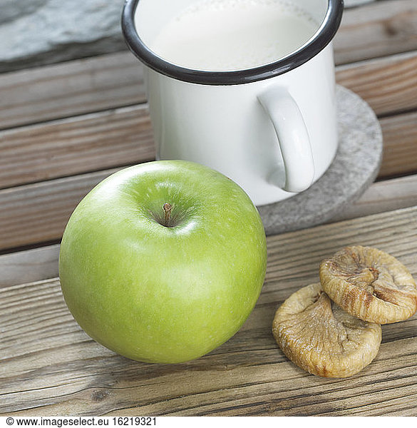 Green apple  dried figs and mug of milk  close-up