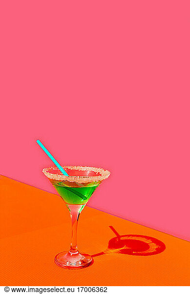 Green drink with straw against pink background