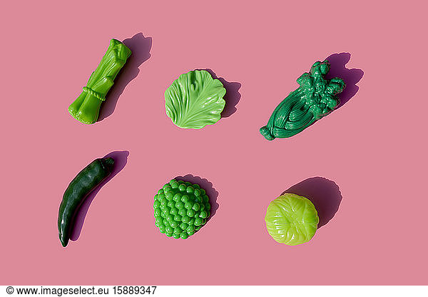 Green plastic vegetables against pink background