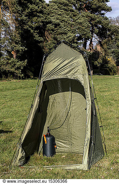 Green shower tent pitched on a meadow.
