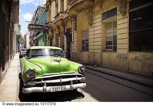 Green vintage car parked on street amidst buildings