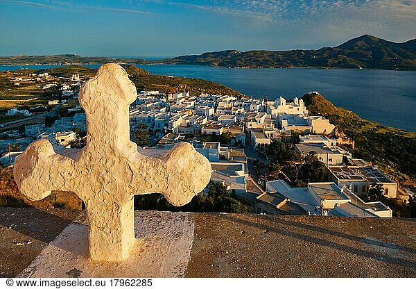 Griechisch-Orthodoxes Christentum Konzept Hintergrund  Fokus Blumen  christliche Kreuz mit Plaka Dorf auf Milos Insel im Hintergrund auf Sonnenuntergang  Plaka Stadt  Milos Insel  Griechenland  Europa