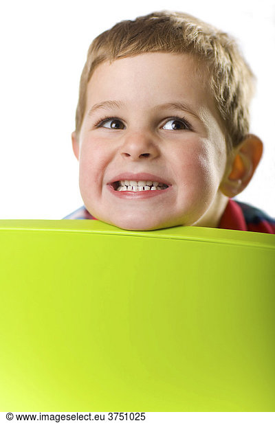 Grinning boy looking over the back of a chair