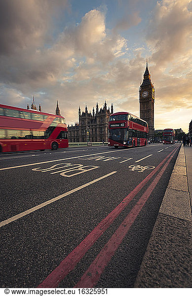 Großbritannien  London  rote Busse fahren an der Westminster Bridge vorbei  im Hintergrund der Turm Big Ben bei Sonnenuntergang