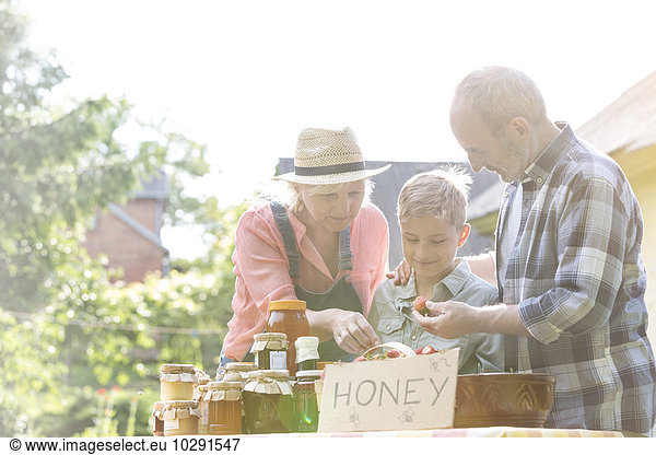 Großeltern und Enkel verkaufen Honig am Bauernmarktstand