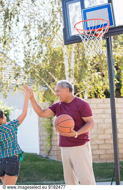 Großvater und Enkelin beim Basketballkorb hoch fünfzig