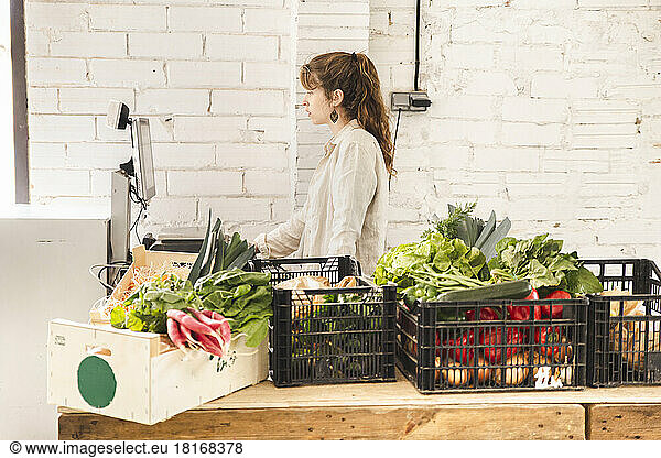 Grocer using weight scale in greengrocer shop