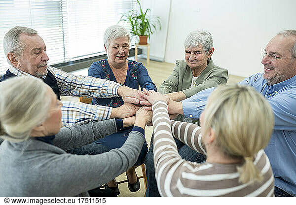 Group of active seniors stacking hands  symbolizing solidarity