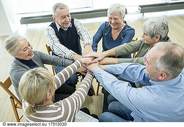 Group of active seniors stacking hands  symbolizing solidarity