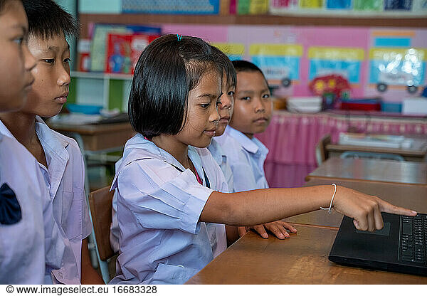 Group of Asian elementary school students Learning to use Laptop