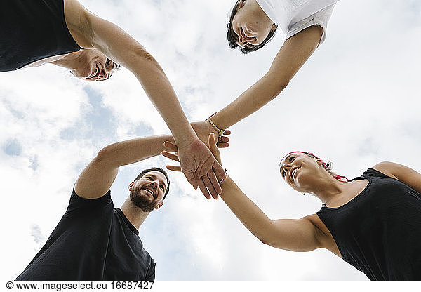 Group of fit people giving a high five for motivation outdoors