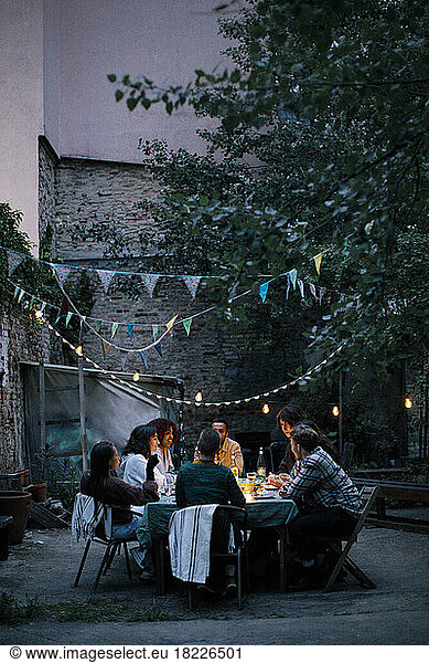 Group of friends enjoying during dinner party in decorated back yard