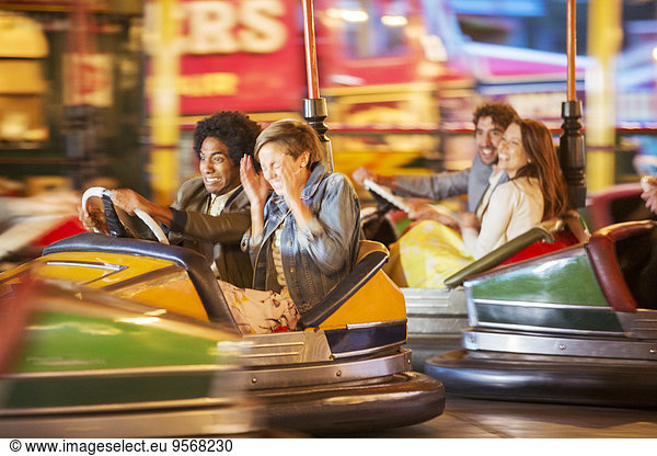 Group of friends having fun on bumper car ride in amusement park