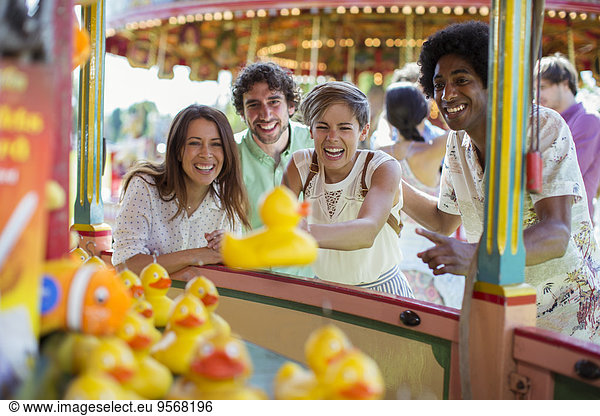 Group of friends having fun with fishing game in amusement park