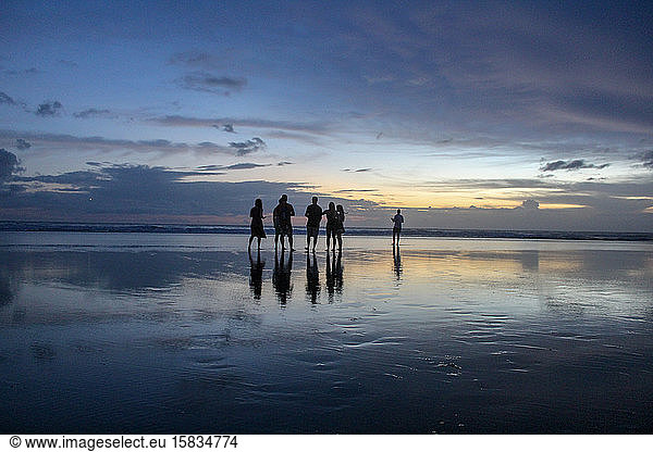 Group of friends on the beach in Bali after sunset.