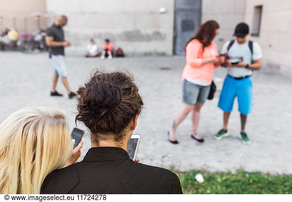 Group of friends playing augmented reality game with mobile phones