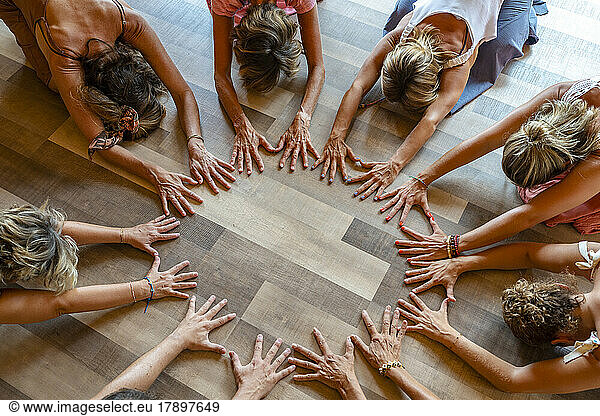 Group of friends practicing child pose with hands on floor