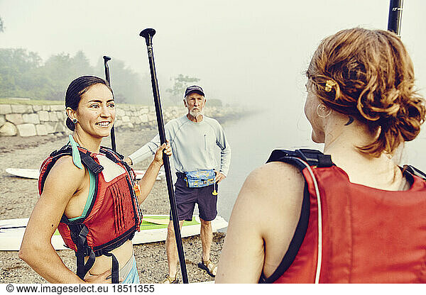 Group of friends prepare for standup paddle board adventure in the fog