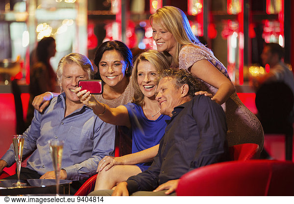 Group of mature friends taking selfie in nightclub