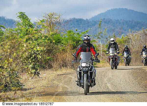 group of men riding their ADV motorbikes on gravel road in Cambodia