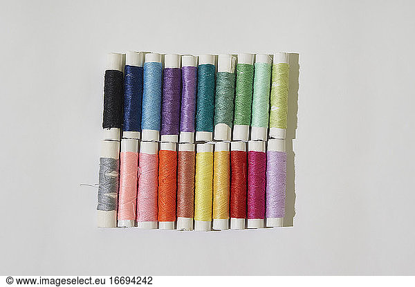 Group of multicolor reel of sewing thread on white background.